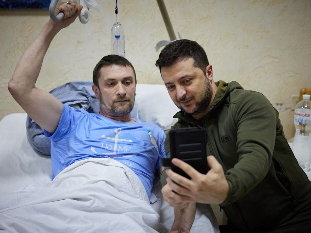 Ukrainian President Volodymyr Zelenskyy snaps a selfie with an injured man laying on a bed during a visit at a military hospital following fighting in the Kyiv region. Picture: Handout / UKRAINIAN PRESIDENTIAL PRESS SERVICE / AFP