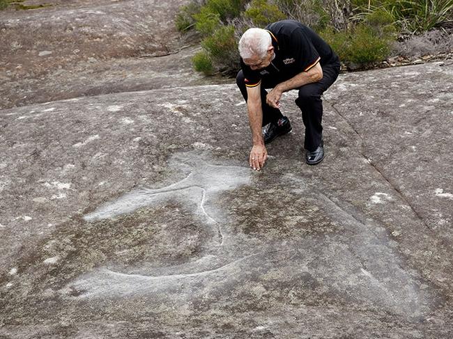 Aboriginal elder Uncle Allen Maddern with a rock carving within the Patyegarang land holding. Picture: Metropolitan Local Aboriginal Land Council