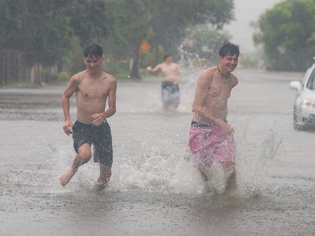 Some local boys play up the street in Railway Estate Townsville as flood waters start to rise. Picture Adam Head