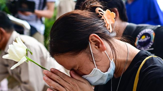 A woman prays while offering a white rose. Picture: AFP