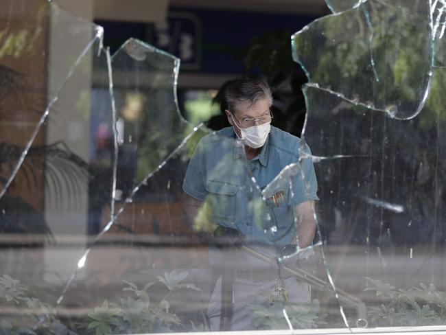 A worker vacuums broken glass from store front in downtown Louisville, Kentucky, the day after protests. Picture: AP Photo/Darron Cummings