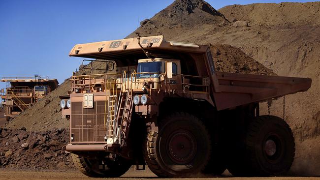 Heavy earth moving trucks at the Tom Price iron ore mine, operated by Rio Tinto Group, are lit up by the afternoon sun in Pilbara, north Western Australia on Wednesday, July 26, 2006. BHP Billiton Ltd., the world's largest mining company, is losing the support of investors and steelmakers for its proposed $128 billion takeover of Rio Tinto Group. Photographer: Jack Atley/Bloomberg News