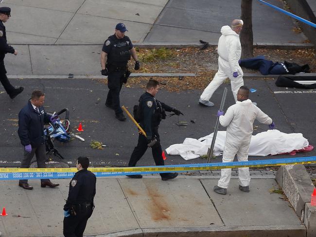 Authorities investigate the scene near a covered body on a bike path. Picture: AP