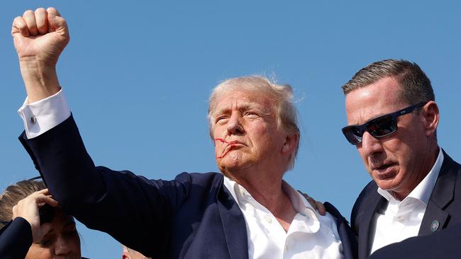 Republican presidential candidate former President Donald Trump pumps his fist as he is rushed offstage during a rally in Butler, Pennsylvania.