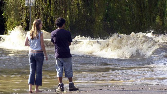 Residents watch as floodwaters race across Wakehurst Parkway after heavy rain hit the area in March. Picture: John Grainger