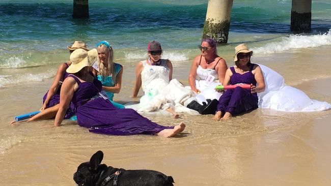 Joanne Colman’s bridal party sitting in the water.