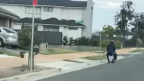 Man caught riding suitcase down Barry Rd, North Kellyville. Image: Jess Kybert.