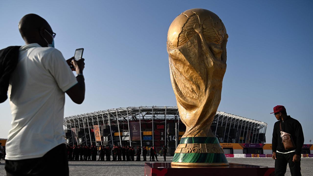 A man takes a picture in front of a replica of the World Cup trophy outside the Stadium 974 in Doha on November 15, 2022, ahead of the Qatar 2022 World Cup football tournament. (Photo by Kirill KUDRYAVTSEV / AFP)