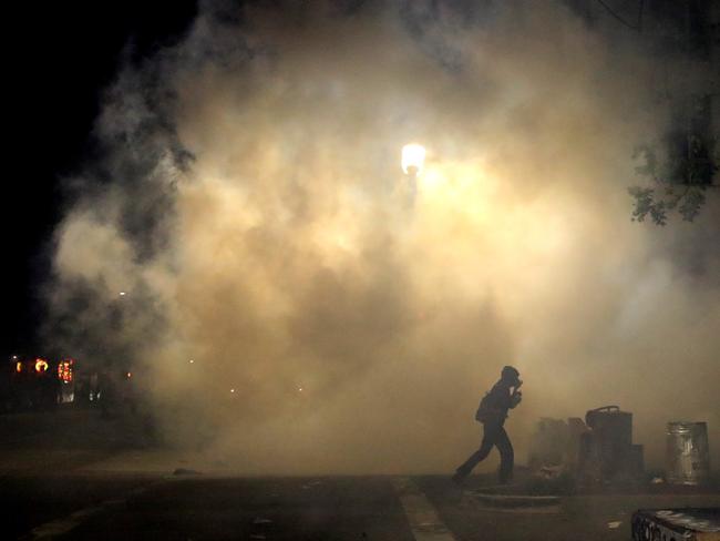 A demonstrator runs through tear gas that was deployed by police officers during a protest in Oakland, California. Picture: Getty