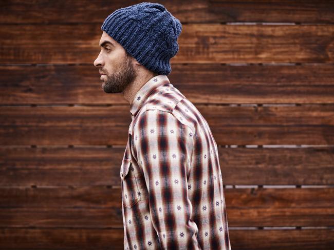 Shot of a handsome young man in trendy winter attire against a wooden background