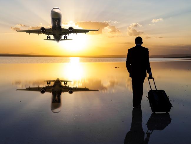 Businessman pulling his luggage and walking against sun while a passenger plane passes over. **PIC IDEA FOR 'NOWHERE' TRAVEL STORY**