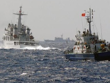 This picture taken from a Vietnam Coast Guard ship on May 14, 2014 shows a China Coast Guard ship (L) blocking the way of a Vietnam Coast Guard ship near to the site of a Chinese drilling oil rig (R, background) being installed at the disputed water in the South China Sea off Vietnam's central coast. Vietnam National Assembly's deputies gathered for their summer session are discussing the escalating tension with China over the South China Sea's contested water. AFP PHOTO/HOANG DINH Nam (Photo credit should read HOANG DINH NAM/AFP/Getty Images)