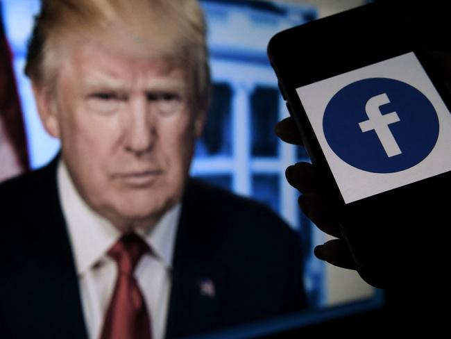 (FILES) In this file photo  illustration, a phone screen displays a Facebook logo with the official portrait of former US President Donald Trump on the background, on May 4, 2021, in Arlington, Virginia. - Facebook's independent oversight board on May 5, 2021 upheld the platform's ban on former US president Donald Trump but called for a further review of the penalty within six months. The board, whose decisions are binding on the leading social network, said Trump "created an environment where a serious risk of violence was possible" with his comments regarding the January 6 rampage by his supporters at the US Capitol. (Photo by Olivier DOULIERY / AFP)