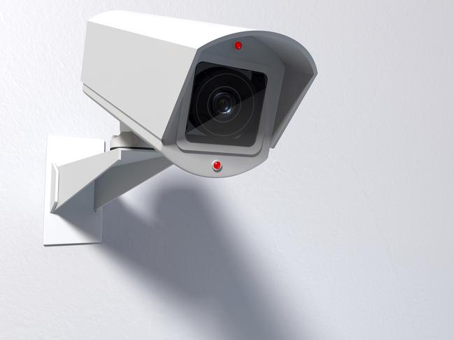 A white wireless surveillance camera with illuminated lights mounted on an isolated white wall with copy space