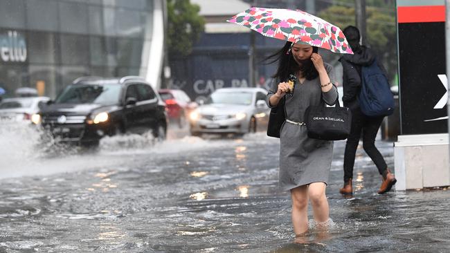 Pedestrians wade through flood waters at the corner of Clarendon and Cecil Street in South Melbourne. Picture: AAP Image/Julian Smith