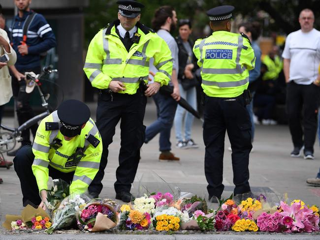 A police officer lays flowers at a pedestrian crossing by Borough Market in London in tribute to the victims of the June 3 attacks. Picture: Justin Tallis