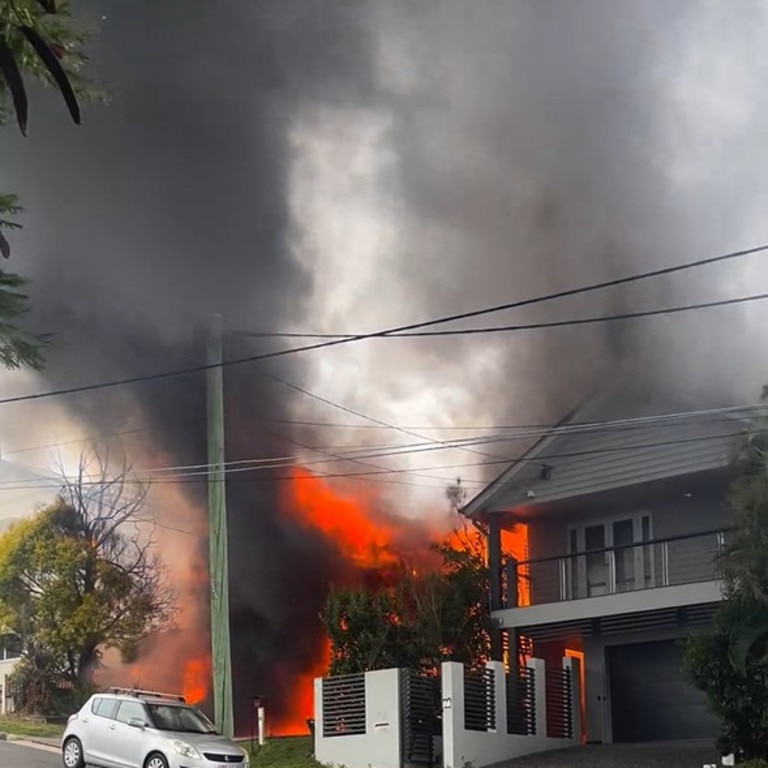 Fire crews are battling multiple house fires in an up-market Brisbane street in the inner north after a blaze spread to neighbouring homes.