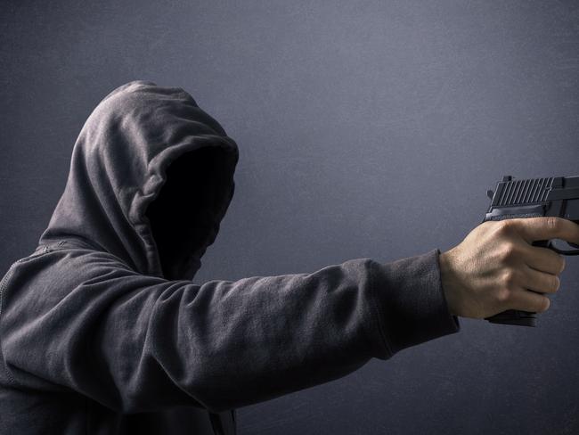 Hooded man with a gun in the dark istock image