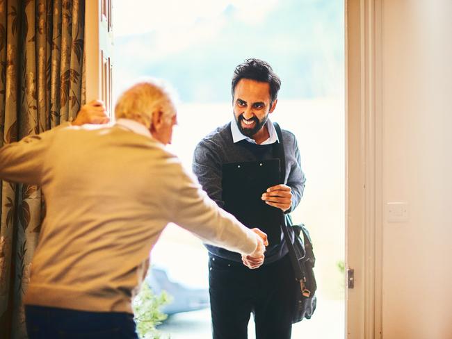 Young male community healthcare worker being welcomed by a senior man at his home; Aged care home care visit, senior generic