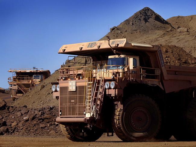 Heavy earth moving trucks at the Tom Price iron ore mine, operated by Rio Tinto Group, are lit up by the afternoon sun in Pilbara, north Western Australia on Wednesday, July 26, 2006. BHP Billiton Ltd., the world's largest mining company, is losing the support of investors and steelmakers for its proposed $128 billion takeover of Rio Tinto Group. Photographer: Jack Atley/Bloomberg News