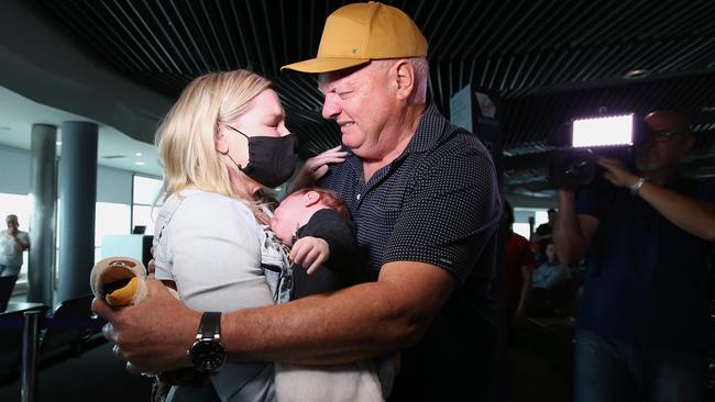 Grandfather Col Binding (R) meets his grandson Ted for the first time, with daughter Lauren Somers, after both Ted and Lauren arrived on the first flight to Brisbane from Melbourne since the Queensland border reopened. Picture: Jono Searle/Getty Images