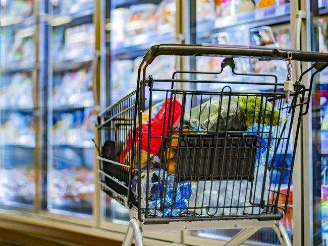 A shopping cart with grocery products in a supermarket