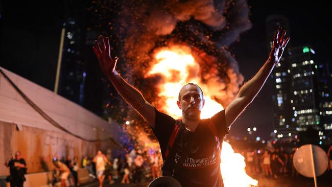 A man raises his arms in front of burning wooden pallets as protesters block Tel Aviv's Ayalon highway. Picture: AFP