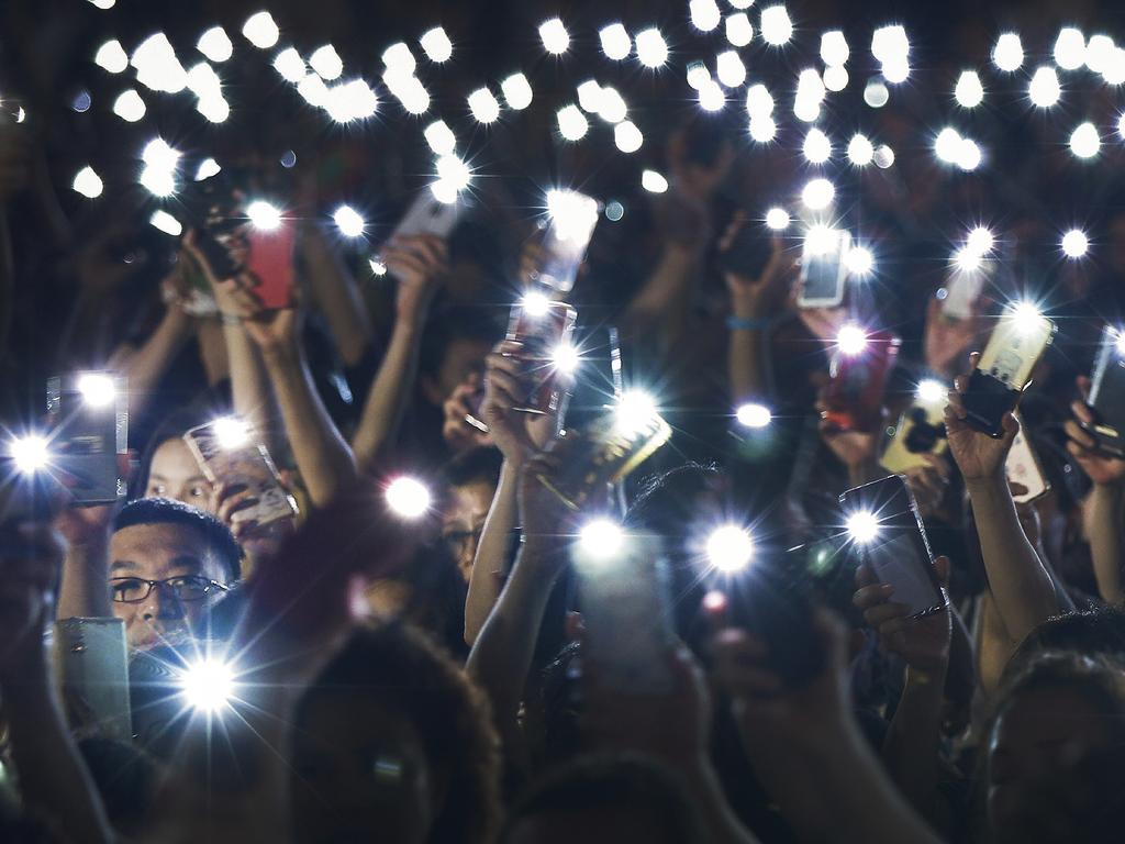 Attendees wave their lit mobile phones during a rally by mothers in support of students risking their lives to make a stand against the bill. Picture: AP Photo/Andy Wong