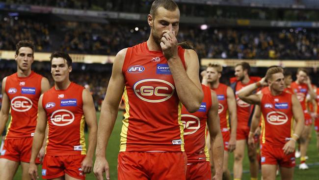 Co-captain Jarrod Witts leads a dejected Gold Coast off during the club’s 18 match losing run. Picture: AAP Image/Daniel Pockett.