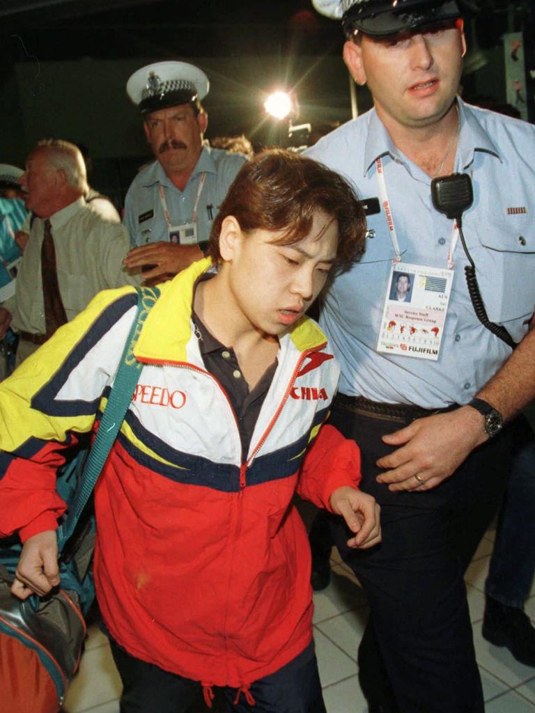 Chinese swimmer Yuan Yuan is escorted by a policeman on her arrival in Perth, January 8, 1998. Picture: AP Photo/Mike Fiala