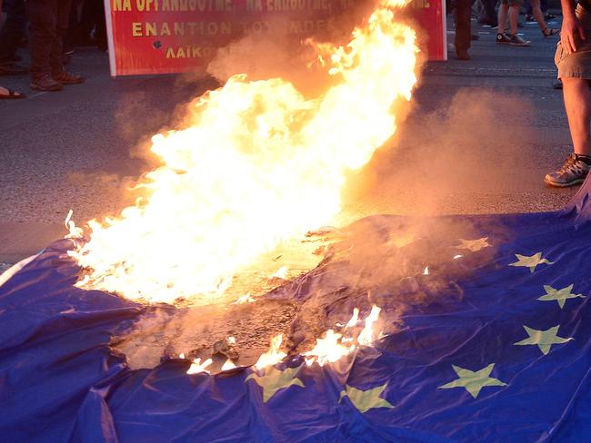 An anti-EU protester burns an EU flag outside the European Comission offices in Athens on July 2, 2015. Greece's government and international creditors raised the stakes on July 2 over a weekend referendum seen as decisive for the nearly insolvent EU country's political and financial future. While Prime Minister Alexis Tsipras has urged Greeks to vote 'No' to the austerity measures demanded by international creditors, opposition parties including the centre-right New Democracy are campaigning for a 'Yes' vote in the referendum on July 5. AFP PHOTO / Louisa Gouliamaki