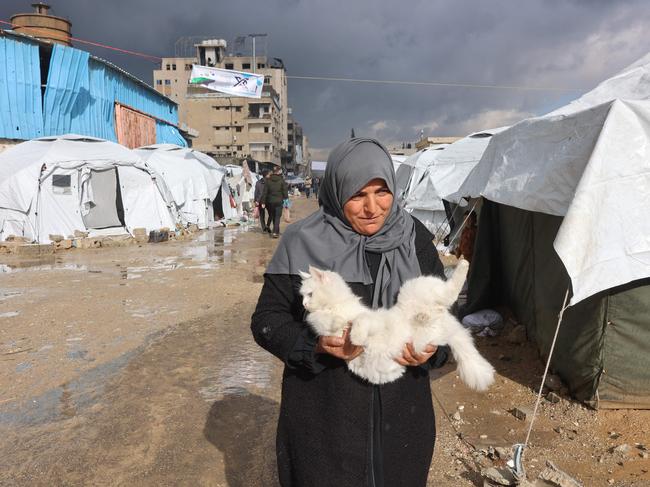 A Palestinian woman carries her cat outside her tent. Picture: AFP