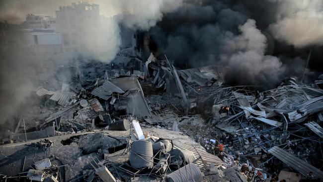 Smoke rises from a levelled building as people gather amid the destruction in the aftermath of an Israeli strike on Gaza City on October 26. Picture: AFP