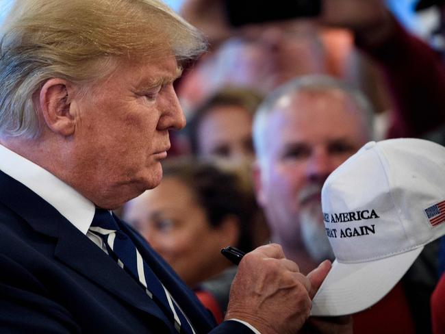 US President Donald Trump signs a hat while meeting with supporters during a Bikers for Trump event at the Trump National Golf Club August 11, 2018 in Bedminster, New Jersey. - Trump welcomed approximately 180 bikers made up of Veterans, law enforcement, supporters and members from the “Bikers for Trump” New Jersey chapter. (Photo by Brendan Smialowski / AFP)