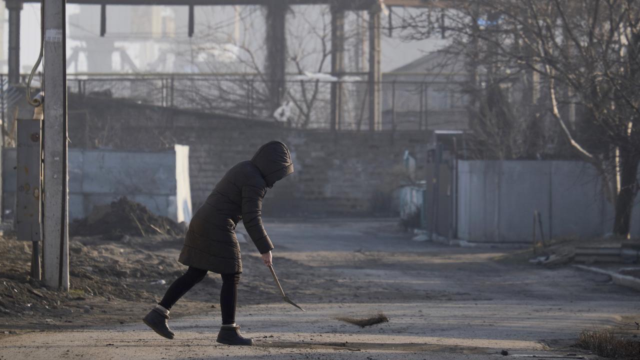 A local resident fills a pothole outside her house near the port of Berdyansk on the Azov Sea on February 16, 2022 in Berdyansk, Ukraine. Picture: Pierre Crom/Getty Images