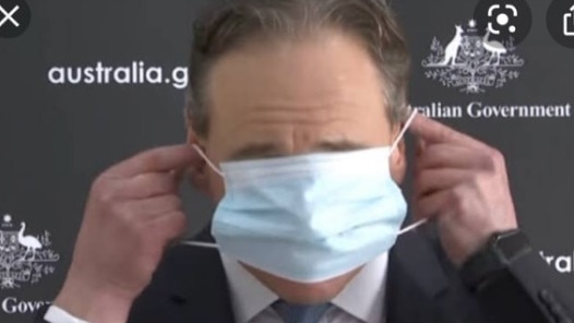 Health Minister Greg Hunt puts on a mask.