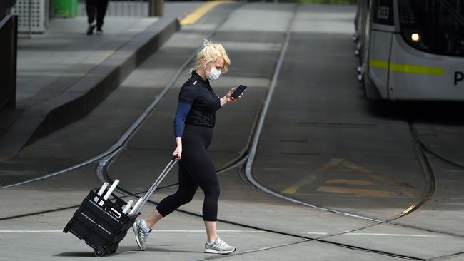 A woman crosses a near-deserted street in Melbourne on Sunday. Picture: AFP)