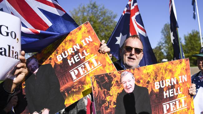 Child sex abuse victim Michael Advocate holds up placards outside the High Court of Australia in Canberra, Wednesday, March 11, 2020 for George Pell's final appeal. (AAP Image/Lukas Coch)