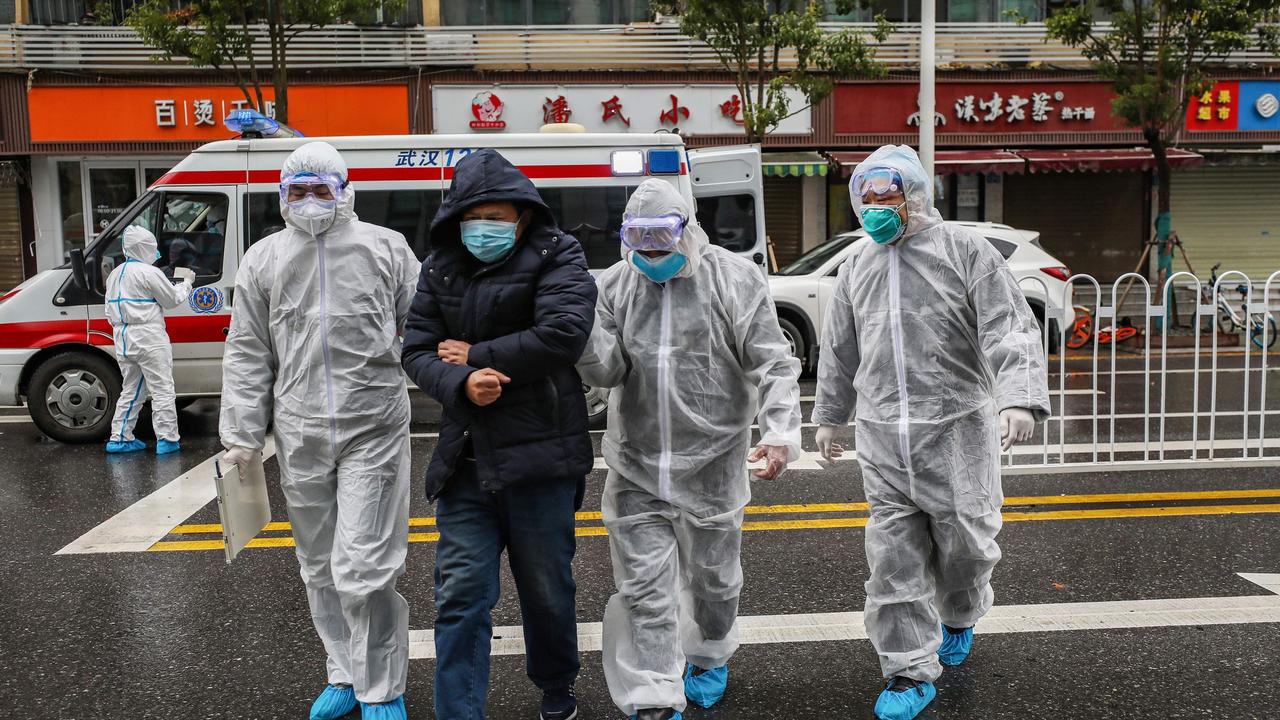 Medical staff members wearing protective clothing to help stop the spread of a deadly virus accompanying a patient as they walk into a hospital in Wuhan.