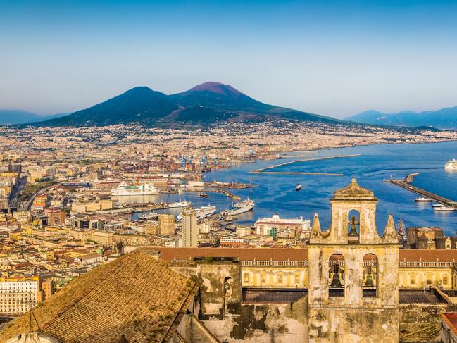 Scenic picture-postcard view of the city of Napoli (Naples) with famous Mount Vesuvius in the background in golden evening light at sunset, Campania, Italy.