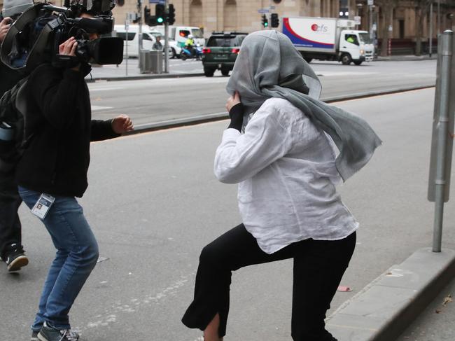 MELBOURNE, AUSTRALIA - NewsWire Photos, JULY 11, 2024. Tyler Garth, 25, covers her face from waiting media as she made her first appearance at the Melbourne Magistrates Court on 292 charges. Police allege she falsified fine nominations while working as a contractor with Fines Victoria. Picture: NewsWire / David Crosling