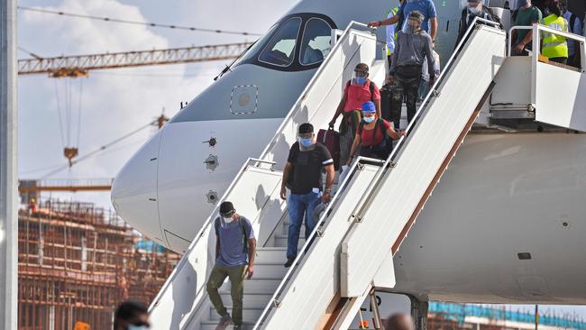 Passengers disembark from a Qatar Airways aircraft upon their arrival at the Velana International Airport in Male on July 15, 2020. - The Maldives formally reopened for tourists on July 15 with a water salute for a commercial airliner bringing holiday makers to the upmarket destination where foreigners will get free coronavirus tests. (Photo by Ahmed SHURAU / AFP)