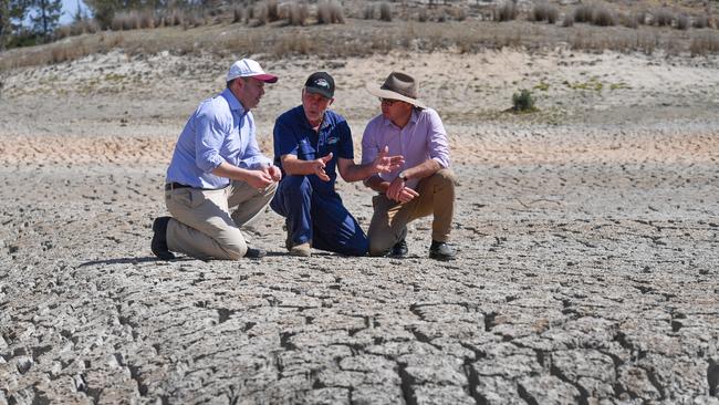 Treasurer Josh Frydenberg, orchard owner Dino Rizzato and Drought Minister David Littleproud in a dried up dam at Cottonvale apple orchard, outside the drought-ravaged town of Stanthorpe.