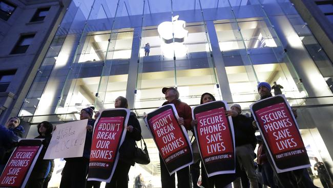 FILE - In this Tuesday, Feb. 23, 2016, file photo, protesters carry placards outside an Apple store in Boston. Tech companies, security experts and civil liberties groups are filing court briefs supporting Apple in its battle with the FBI. The groups oppose a judge’s order that would require Apple to help federal agents hack an encrypted iPhone used by a San Bernardino mass shooter. (AP Photo/Steven Senne, File)