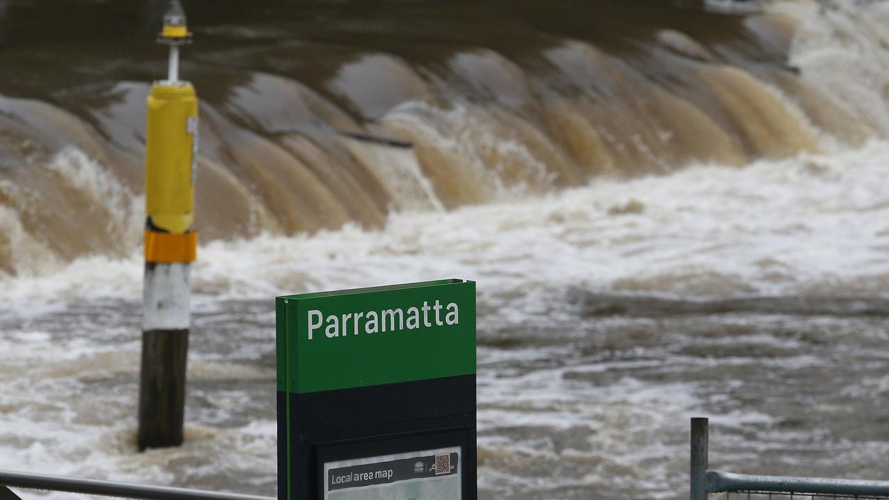 Water from the swollen Parramatta River spills over the weir at the Charles Street Wharf. An east Coast low hits Sydney after a week of heavy rain. Picture: John Appleyard