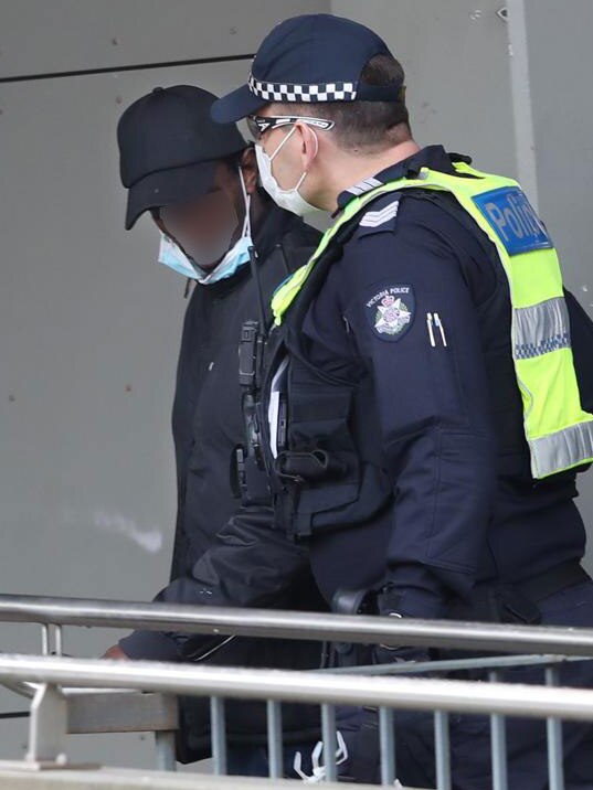 Police escort a man back into the building after he was spotted trying to leave one of the locked down Melbourne towers. Picture: David Grosling