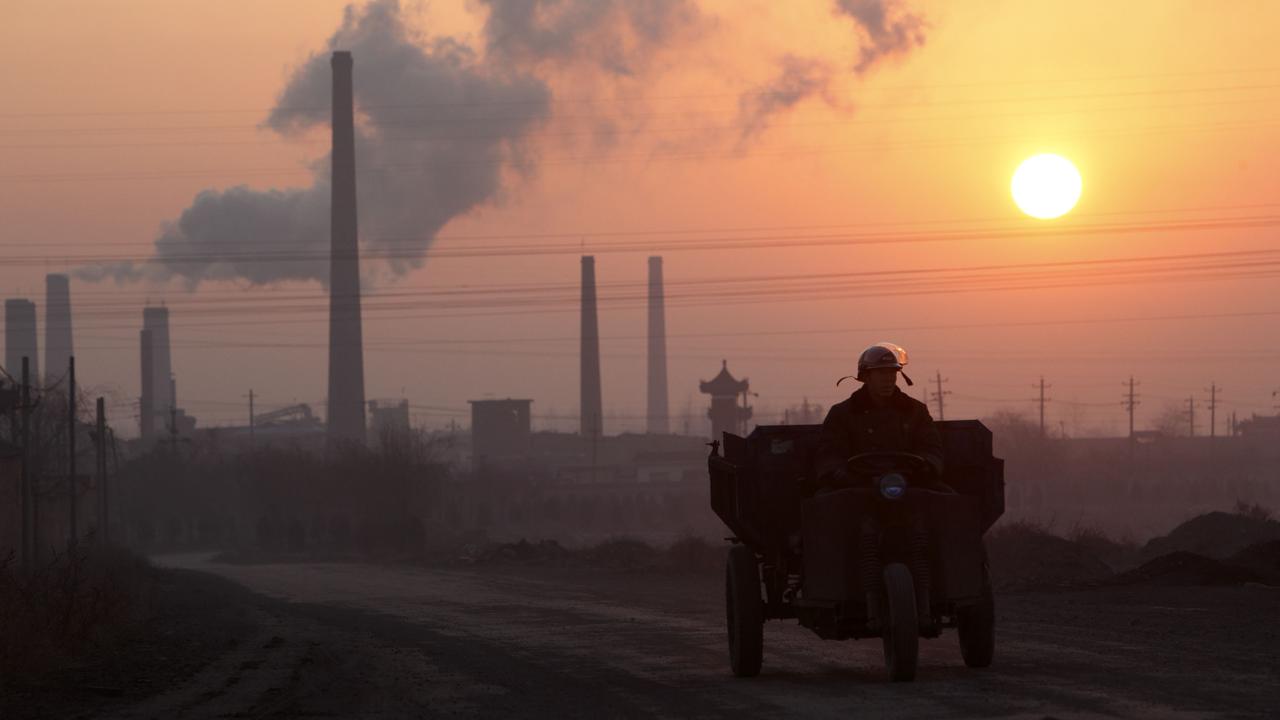 A man drives past a coking factory at sunrise in Shanxi province, China. Photographer: Qilai Shen/Bloomberg