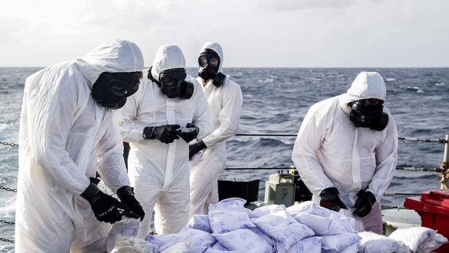 Personnel from HMAS Darwin prepare to destroy the seized heroin.