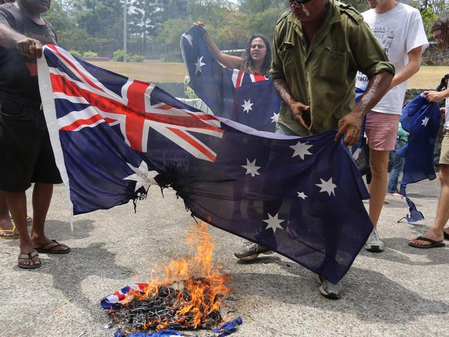 Aboriginal protesters burn an Australian flag during a rally in coincidence with the G20 summit in Brisbane, Australia, Sunday, Nov. 16, 2014.(AP Photo/Dean Saffron)