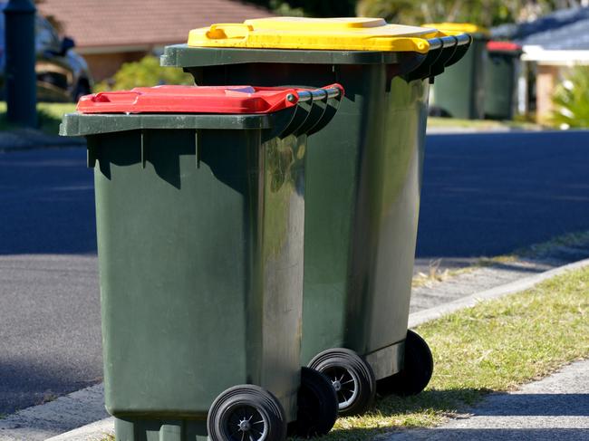 Focus on two Rubbish bins - red lid is rubbish and yellow lid is recycling